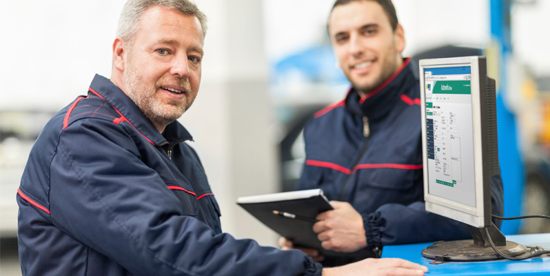 Two mechanics use MAM Autowork online on a desktop computer
