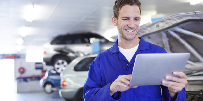 A diligent mechanic using a digital tablet in an auto repair shop